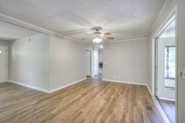 spare room with a ceiling fan, crown molding, visible vents, and wood finished floors