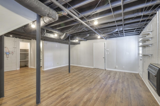 basement featuring baseboards, heating unit, and wood finished floors