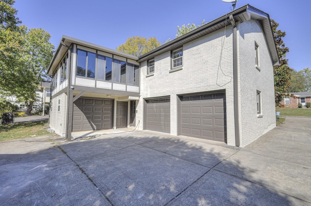 rear view of house with brick siding, driveway, and an attached garage