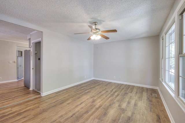 unfurnished room featuring ceiling fan, plenty of natural light, a textured ceiling, and hardwood / wood-style flooring