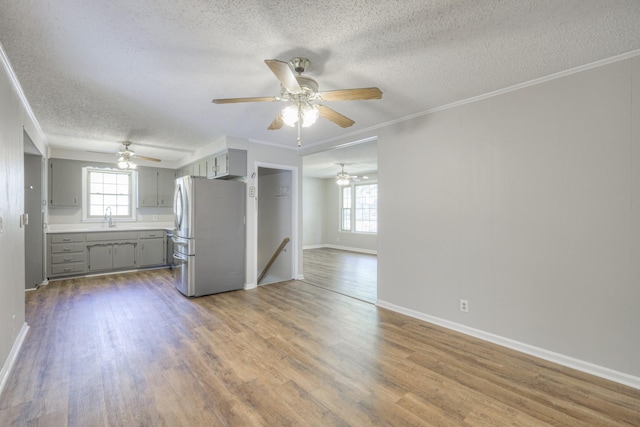 kitchen featuring gray cabinets, freestanding refrigerator, a sink, wood finished floors, and plenty of natural light