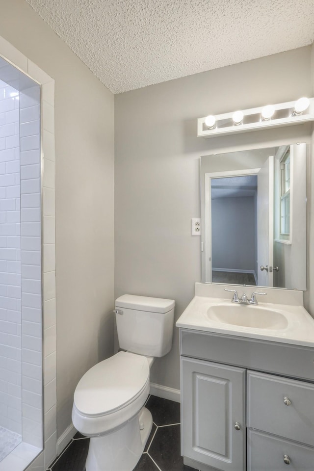 bathroom with vanity, tile patterned flooring, toilet, a textured ceiling, and walk in shower