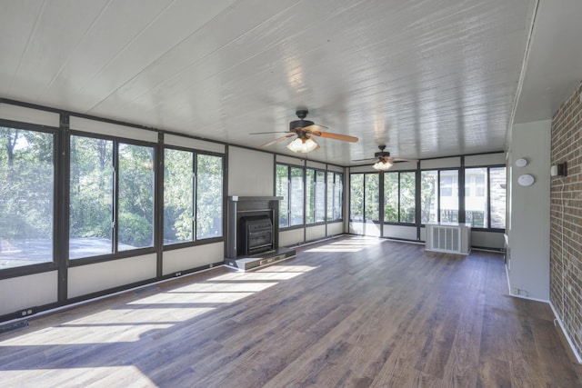 unfurnished sunroom featuring a fireplace with raised hearth, radiator heating unit, visible vents, and a healthy amount of sunlight