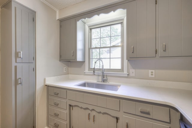 kitchen with gray cabinets, light countertops, a sink, and a textured ceiling