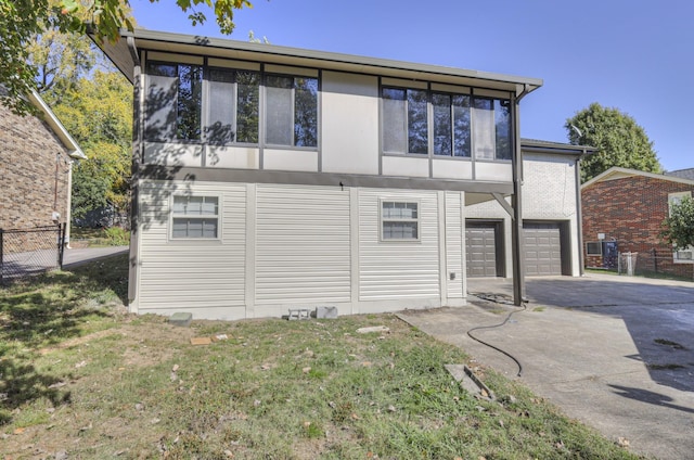 back of house featuring a yard, aphalt driveway, an attached garage, and fence