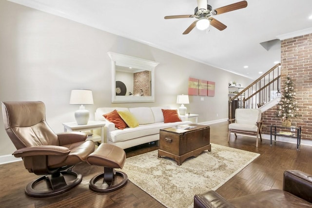 living room with ceiling fan, dark hardwood / wood-style flooring, crown molding, and brick wall