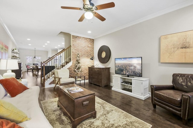 living room with crown molding, dark hardwood / wood-style flooring, ceiling fan, and brick wall