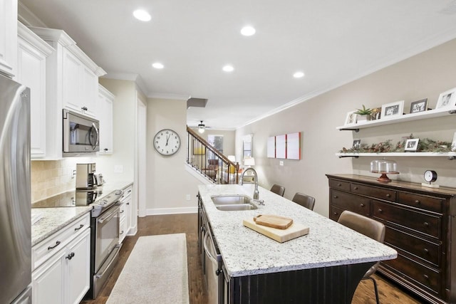 kitchen featuring a kitchen breakfast bar, sink, stainless steel appliances, and an island with sink