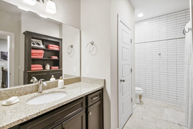 bathroom with toilet, vanity, and tiled shower