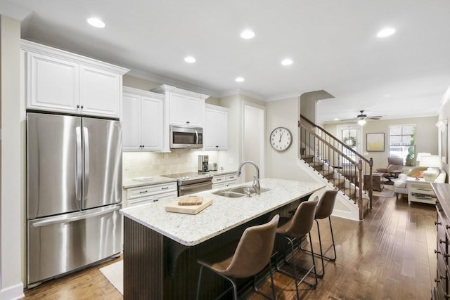 kitchen featuring ceiling fan, sink, stainless steel appliances, a breakfast bar area, and a kitchen island with sink