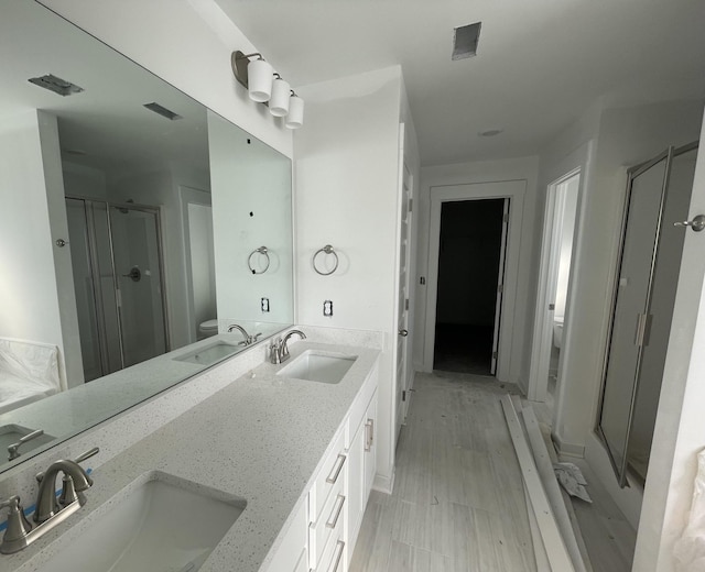 bathroom with an enclosed shower, vanity, and toilet