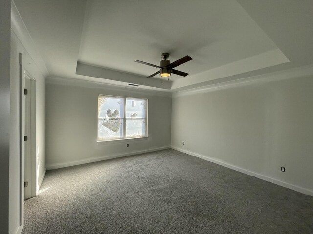 carpeted empty room featuring ceiling fan and a raised ceiling