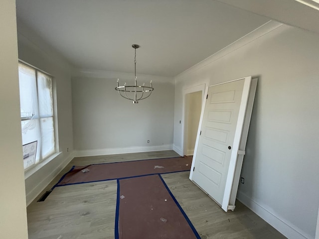 unfurnished dining area with hardwood / wood-style flooring, ornamental molding, and a notable chandelier