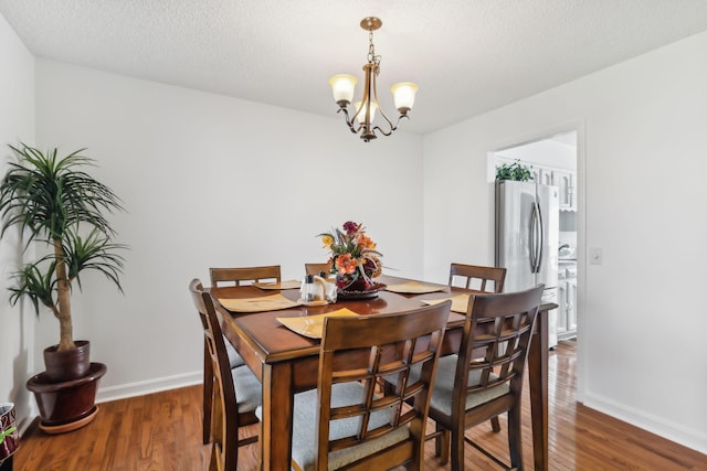 dining room featuring a textured ceiling, dark wood-type flooring, and a chandelier