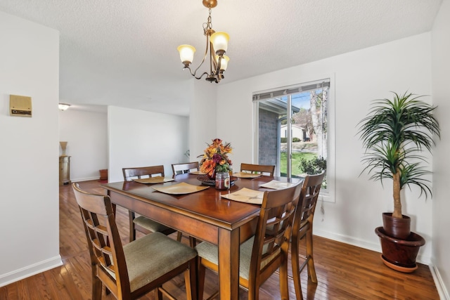 dining space featuring a chandelier, dark wood-type flooring, and a textured ceiling