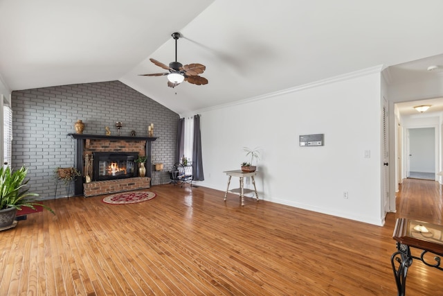 living room with hardwood / wood-style floors, lofted ceiling, crown molding, ceiling fan, and a fireplace