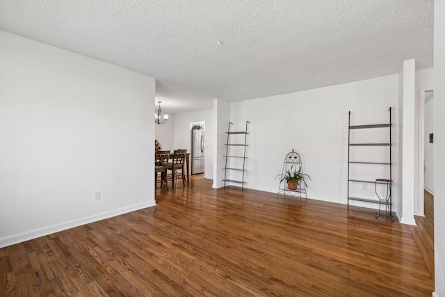 unfurnished room with dark hardwood / wood-style floors, a textured ceiling, and a chandelier