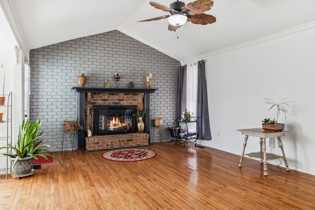 living room featuring a brick fireplace, ornamental molding, vaulted ceiling, ceiling fan, and hardwood / wood-style flooring