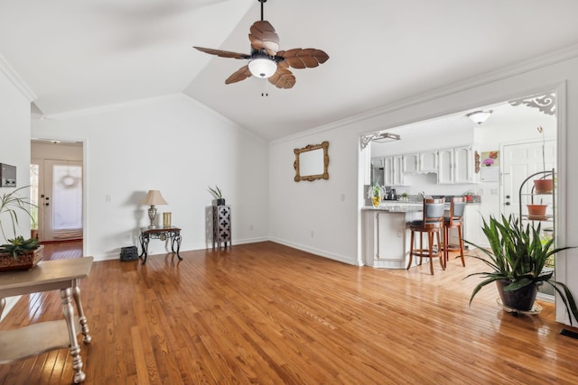 living room with ceiling fan, crown molding, lofted ceiling, and light wood-type flooring