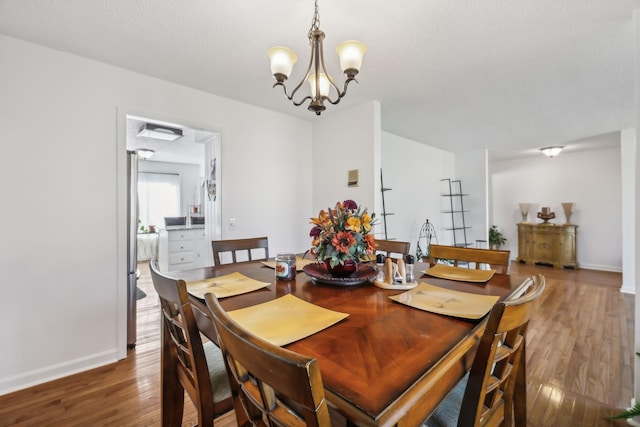 dining space featuring a chandelier, a textured ceiling, and dark hardwood / wood-style flooring