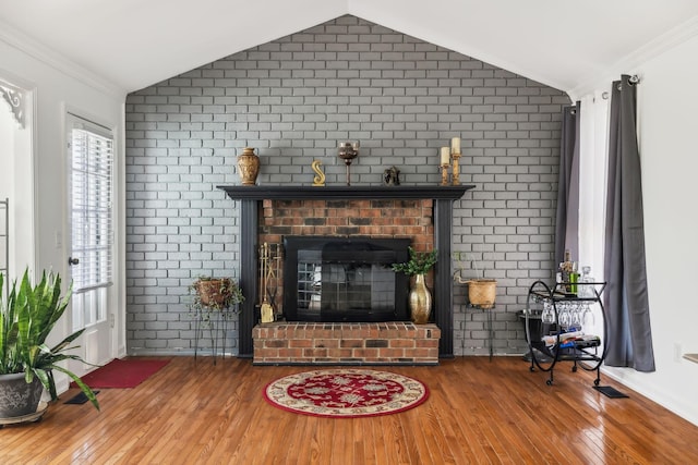 living room with brick wall, vaulted ceiling, and hardwood / wood-style flooring