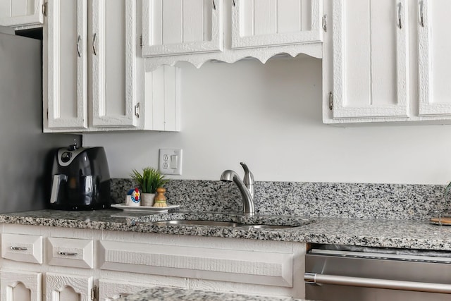 kitchen featuring dishwasher, stone countertops, white cabinets, and sink