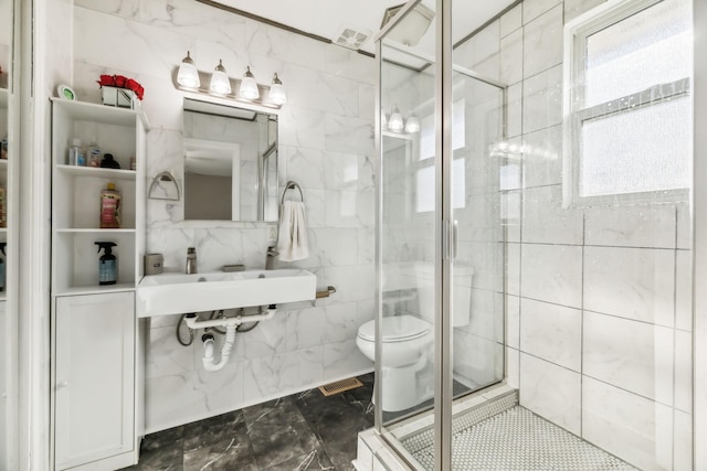 bathroom featuring toilet, a shower with door, and tile walls