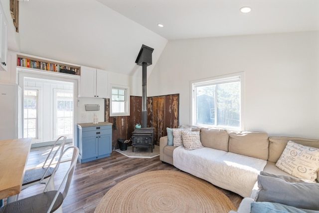 living room with a wood stove, a wealth of natural light, dark wood-type flooring, and vaulted ceiling