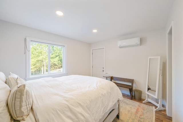 bedroom featuring a wall mounted air conditioner and wood-type flooring