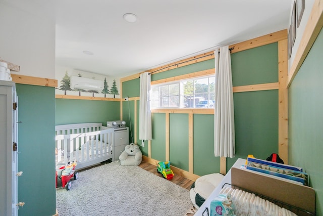 bedroom with wood-type flooring and a nursery area