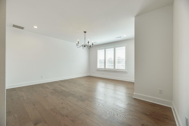 empty room featuring dark hardwood / wood-style flooring and a notable chandelier