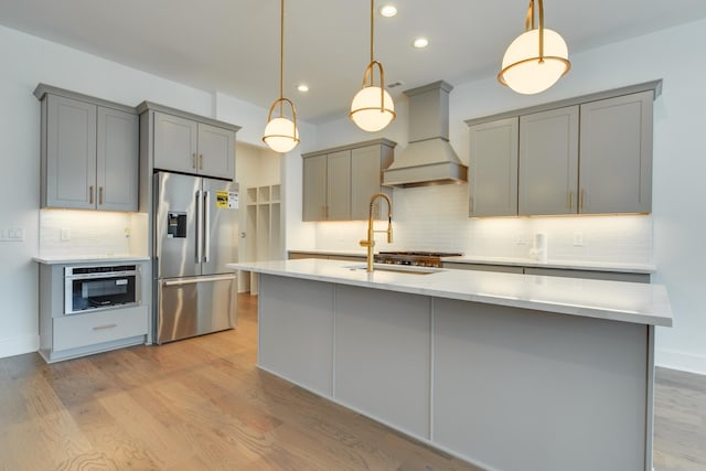 kitchen with pendant lighting, sink, gray cabinets, appliances with stainless steel finishes, and custom range hood