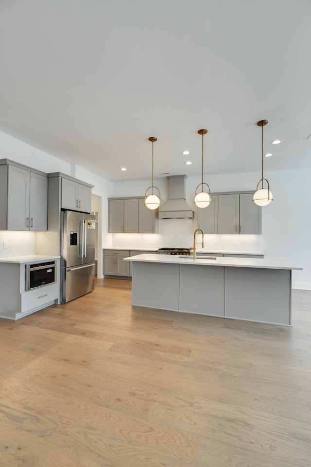 kitchen with gray cabinetry, high end fridge, custom range hood, and tasteful backsplash