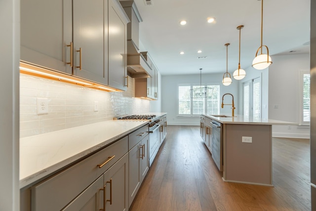 kitchen with a kitchen island with sink, sink, pendant lighting, hardwood / wood-style floors, and gray cabinets