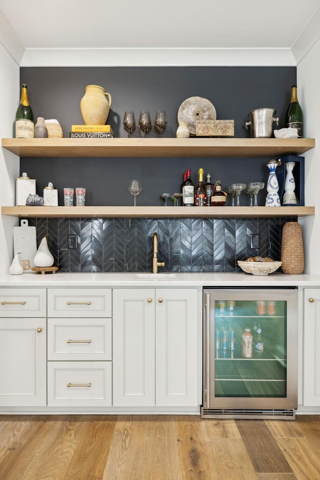 bar featuring wine cooler, white cabinets, sink, and light hardwood / wood-style flooring