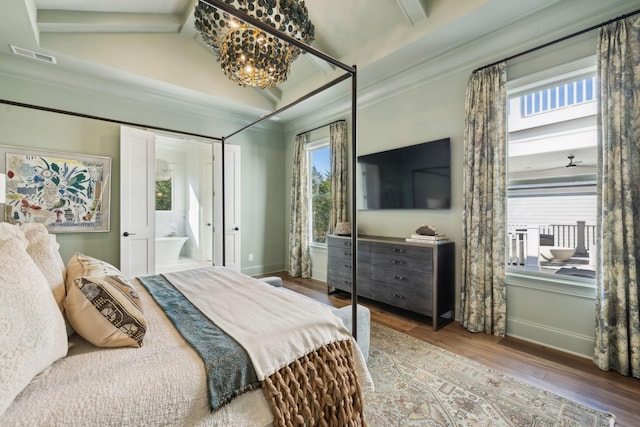 bedroom featuring lofted ceiling, a notable chandelier, ensuite bath, crown molding, and hardwood / wood-style flooring