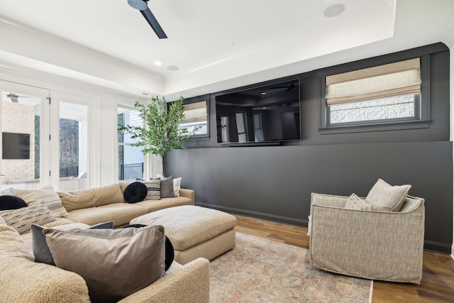 living room with a raised ceiling, ceiling fan, and hardwood / wood-style floors