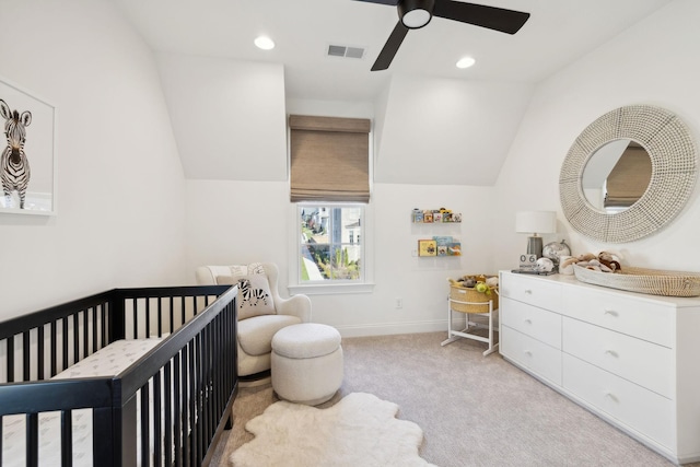 carpeted bedroom with vaulted ceiling, ceiling fan, and a crib