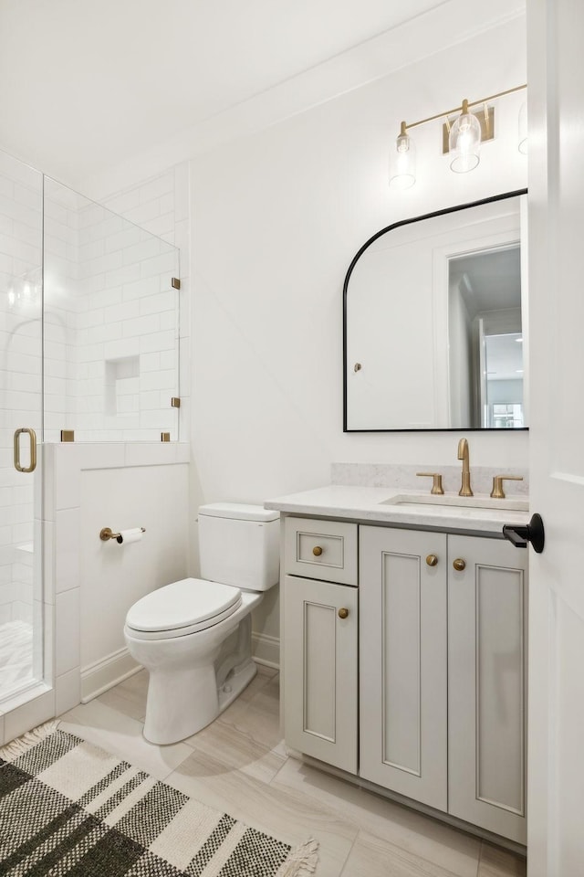 bathroom featuring a shower with shower door, vanity, and toilet