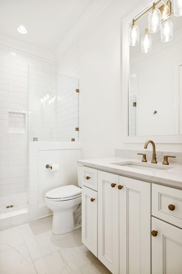 bathroom with toilet, vanity, and tiled shower