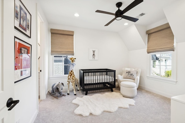 bedroom with ceiling fan, light carpet, vaulted ceiling, and a crib