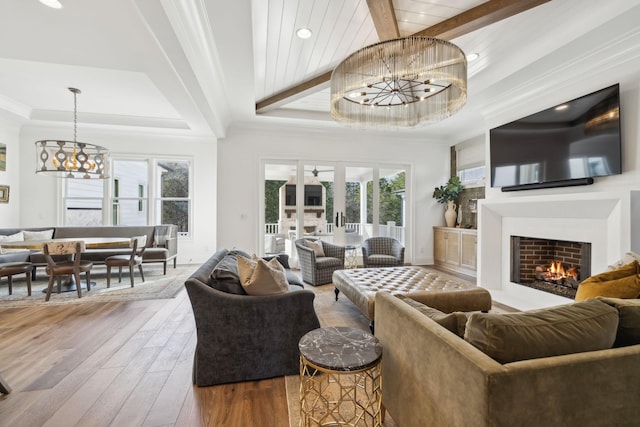 living room with hardwood / wood-style flooring, a raised ceiling, ornamental molding, french doors, and a chandelier