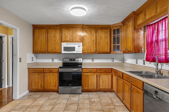 kitchen featuring backsplash, sink, stainless steel appliances, and a textured ceiling