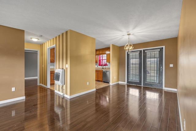 empty room with a notable chandelier, dark hardwood / wood-style flooring, and heating unit