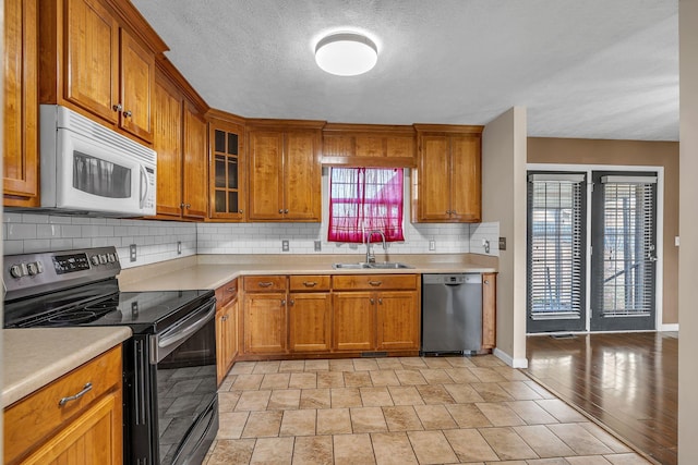 kitchen with a textured ceiling, decorative backsplash, sink, and stainless steel appliances