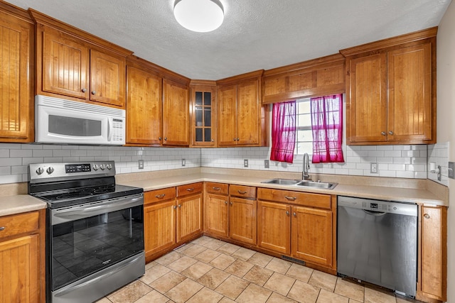 kitchen with decorative backsplash, a textured ceiling, stainless steel appliances, sink, and light tile patterned flooring