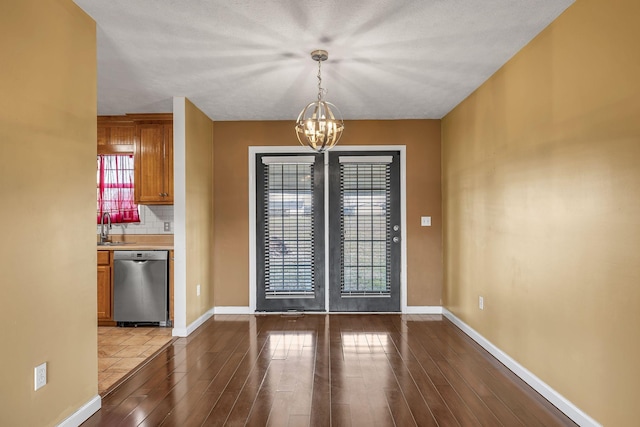 unfurnished dining area with sink, wood-type flooring, and an inviting chandelier