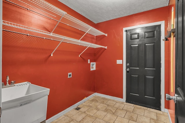 clothes washing area featuring washer hookup, electric dryer hookup, sink, and a textured ceiling