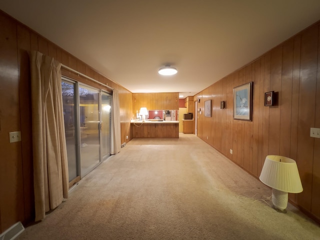 hall with light colored carpet and wooden walls