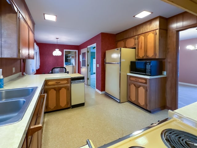 kitchen with sink, fridge, kitchen peninsula, a notable chandelier, and pendant lighting